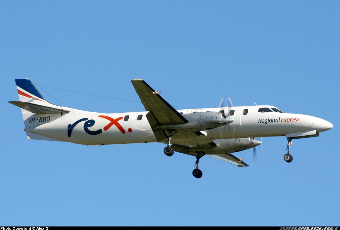 A small passenger plane with propellers at the wings flies in a clear blue sky.